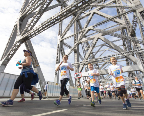 woman and two boys running across story bridge